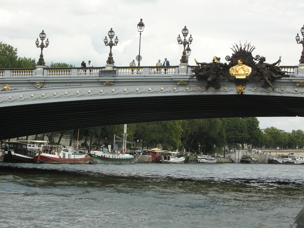 Le pont Alexandre-III vu depuis la Seine, péniches amarrées sur la rive