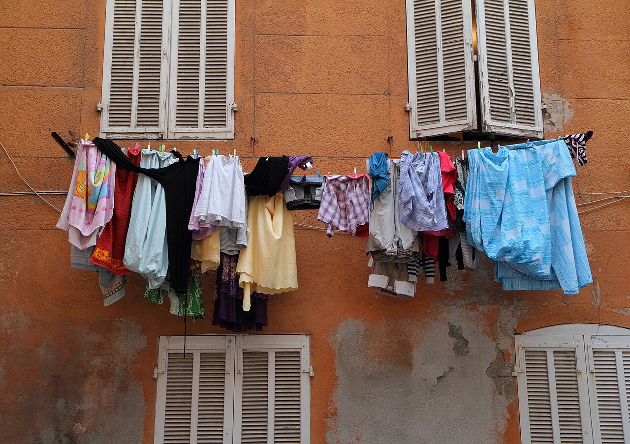 Linge qui sèche entre des volets en bois sur une façade ocre du quartier du Panier