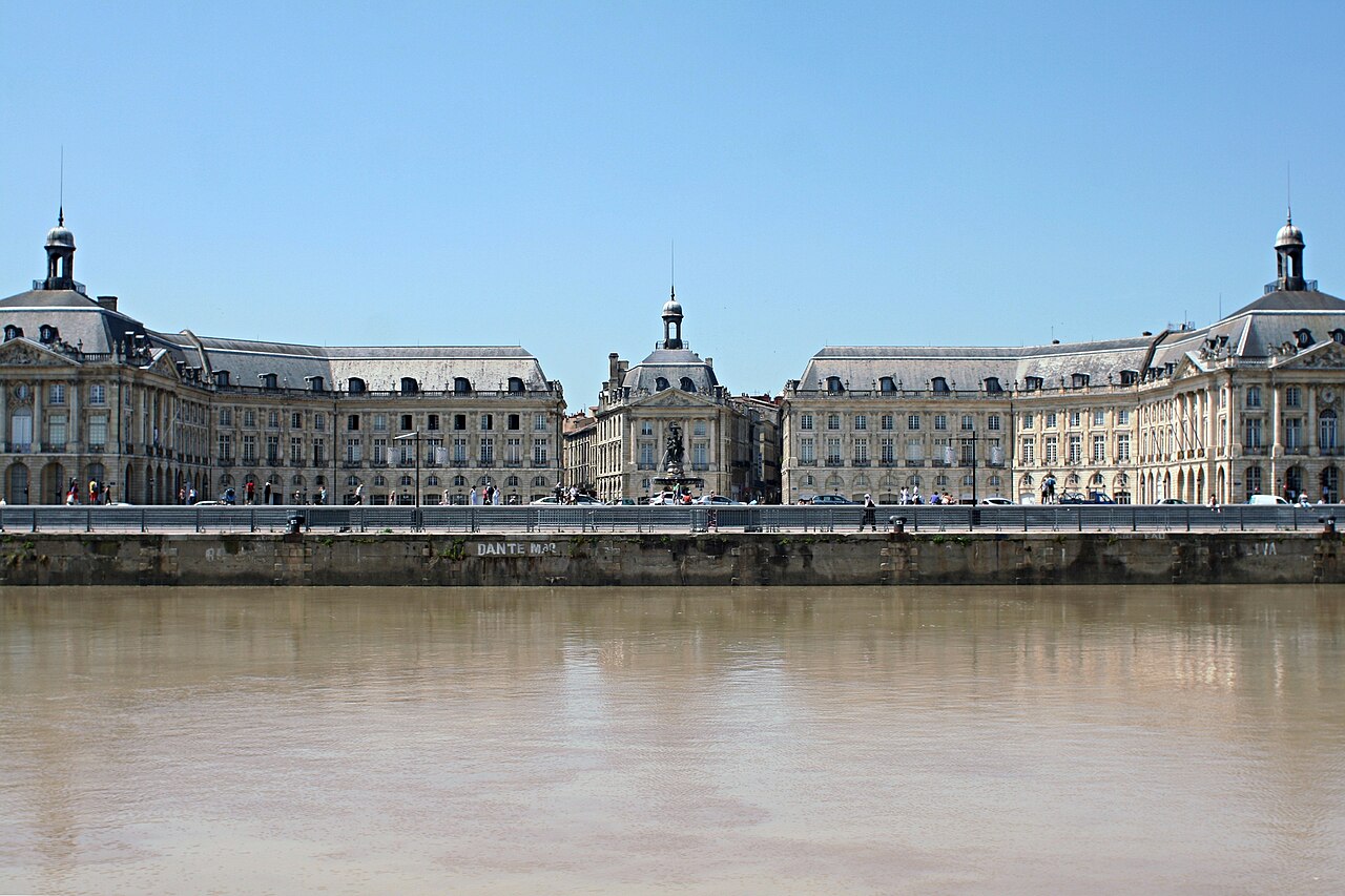 Les façades de la place de la Bourse vues depuis la Garonne, sous un ciel bleu