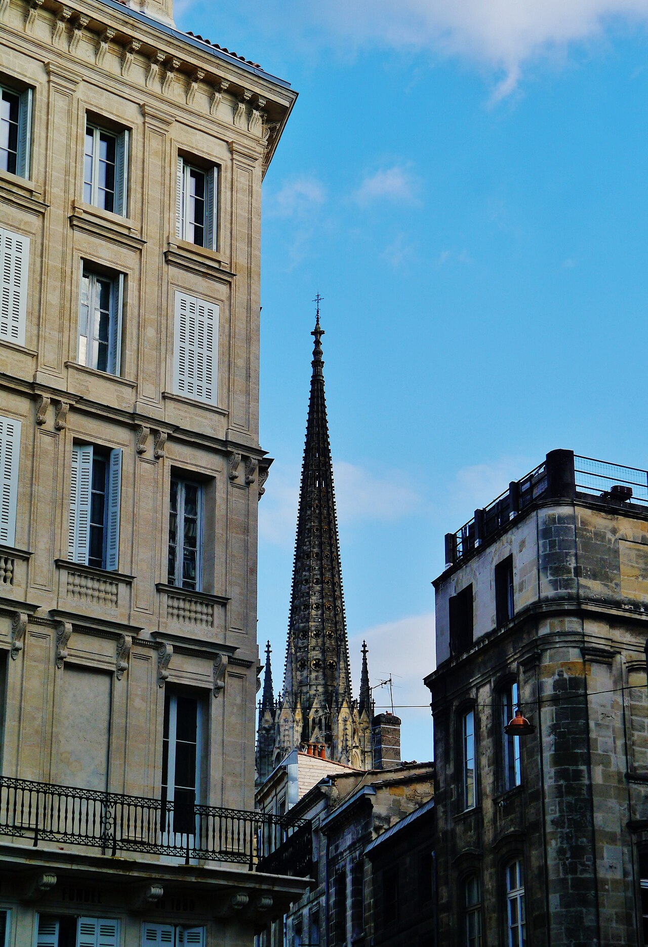 La flèche Saint-Michel s’élevant entre les immeubles de pierre du quartier