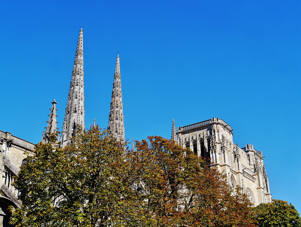 Les deux flèches gothiques du transept nord de la cathédrale Saint-André et la tour Pey-Berland au-dessus des arbres d’automne