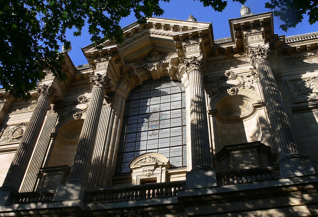 La façade monumentale du Palais des Beaux-Arts de Lille, ses colonnes cannelées et sa grande verrière, vue en contre-plongée sous les feuillages
