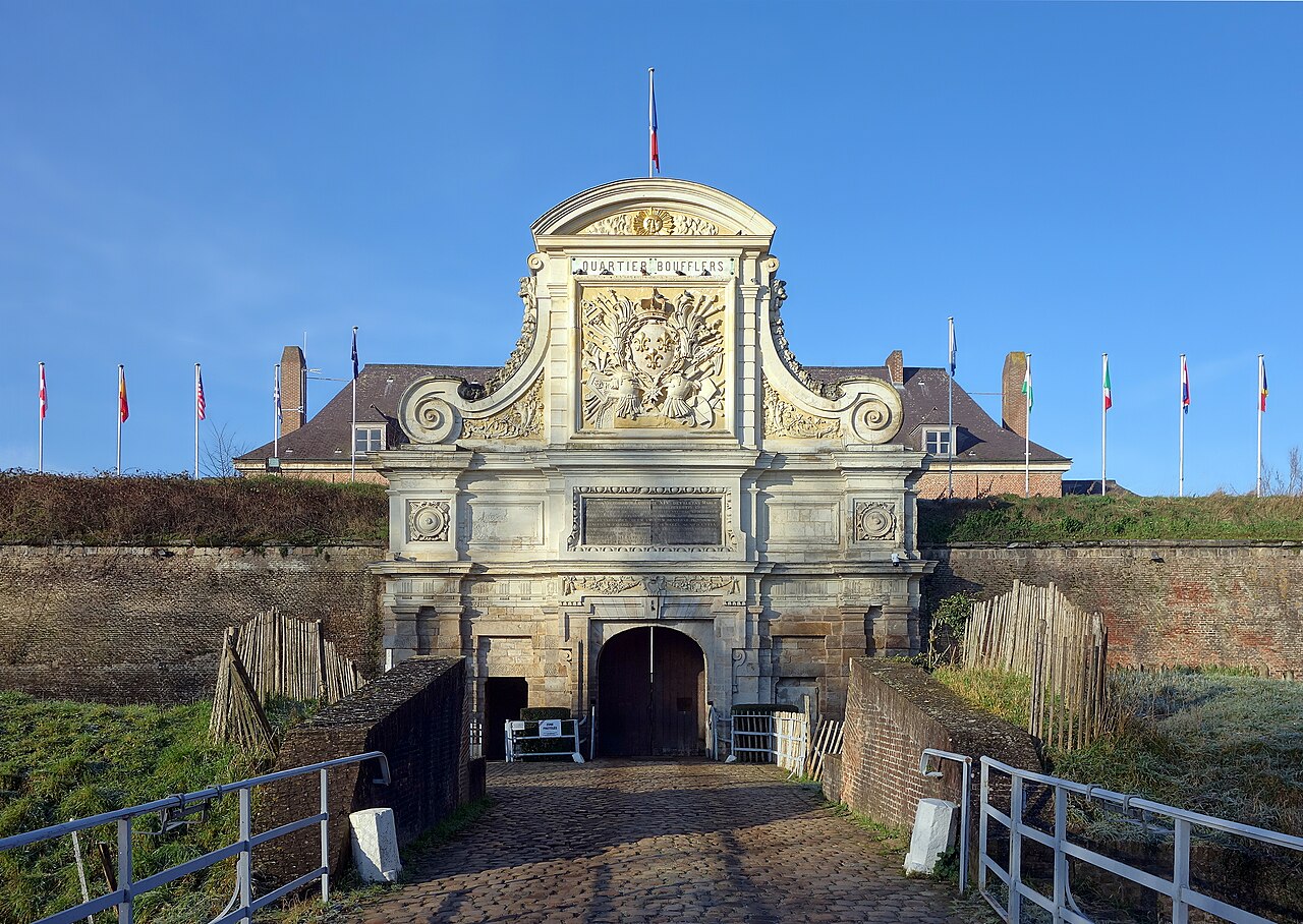 La porte Royale sculptée de la citadelle de Vauban à Lille, au bout d’un pont pavé, entre les remparts de brique et sous un ciel bleu