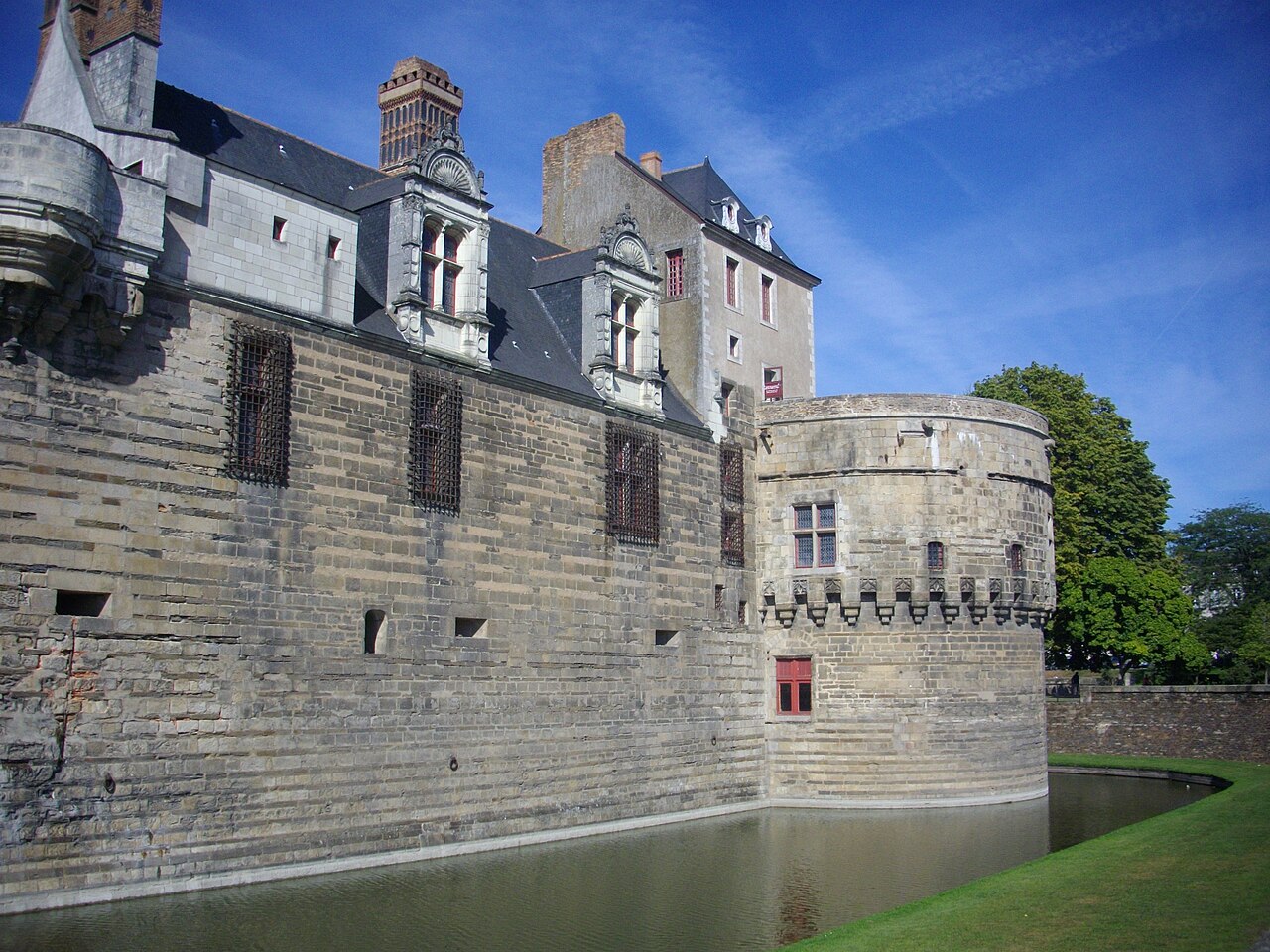 Le rempart sud du château des ducs de Bretagne à Nantes et sa tour de la Rivière, au-dessus des douves en eau, sous un ciel bleu