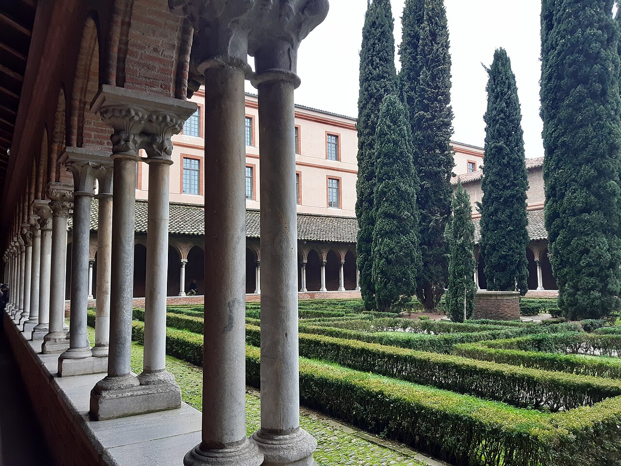 Les colonnettes jumelées du cloître du couvent des Jacobins à Toulouse, devant le jardin de buis et ses grands cyprès