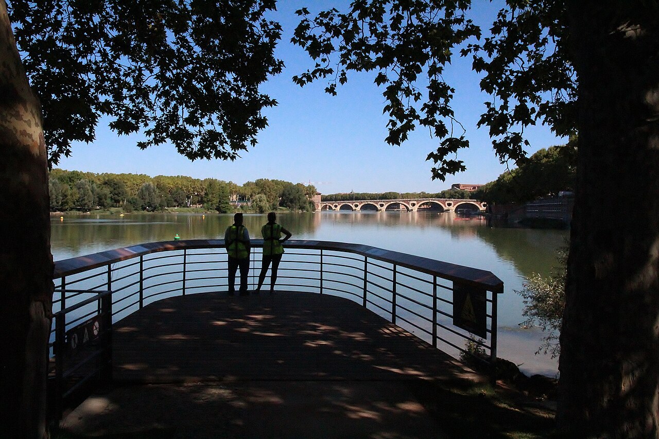 La Garonne à Toulouse vue d’un belvédère ombragé de la prairie des Filtres, avec au loin les arches de brique du Pont-Neuf