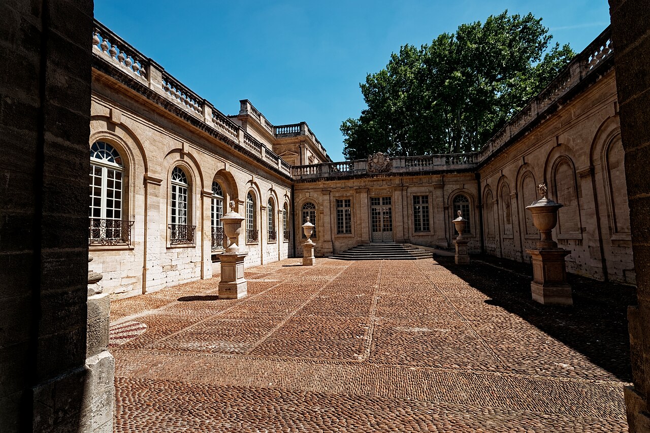 La cour pavée de galets de l’hôtel de Villeneuve-Martignan, siège du musée Calvet à Avignon, ses façades classiques à balustres et ses vases de pierre