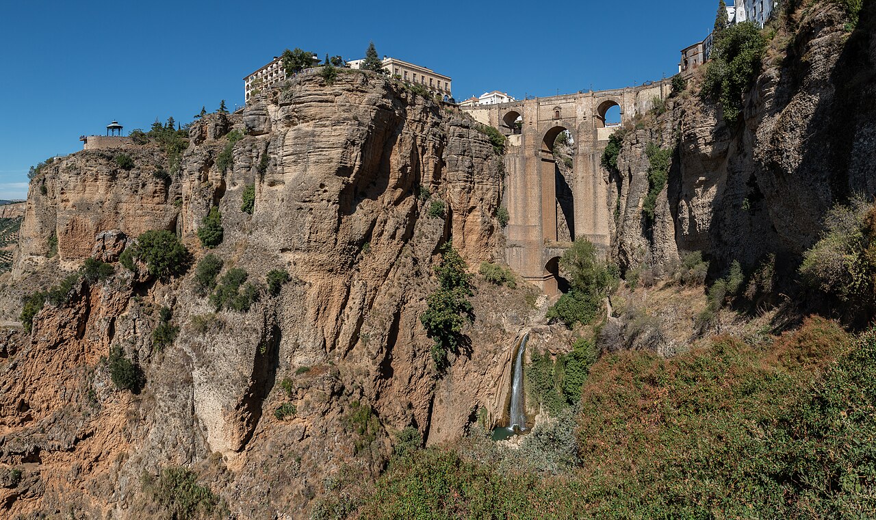 Le Puente Nuevo de Ronda, en Andalousie, enjambant les gorges du Tajo entre deux falaises couronnées de maisons blanches, une cascade au pied du pont