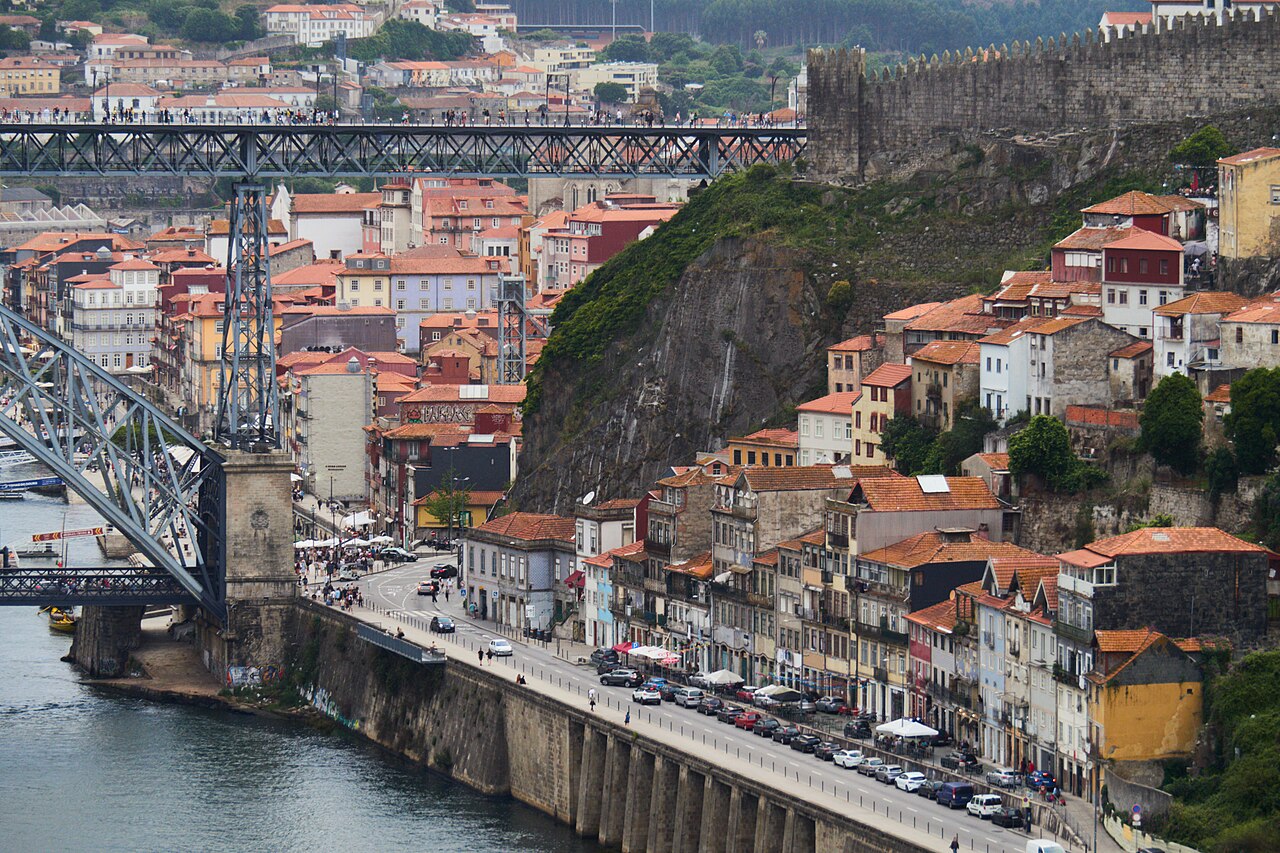 Les maisons aux toits orange de Porto étagées au-dessus du Douro, le pont Luís I et la muraille fernandine, la route des quais de la Ribeira au premier plan