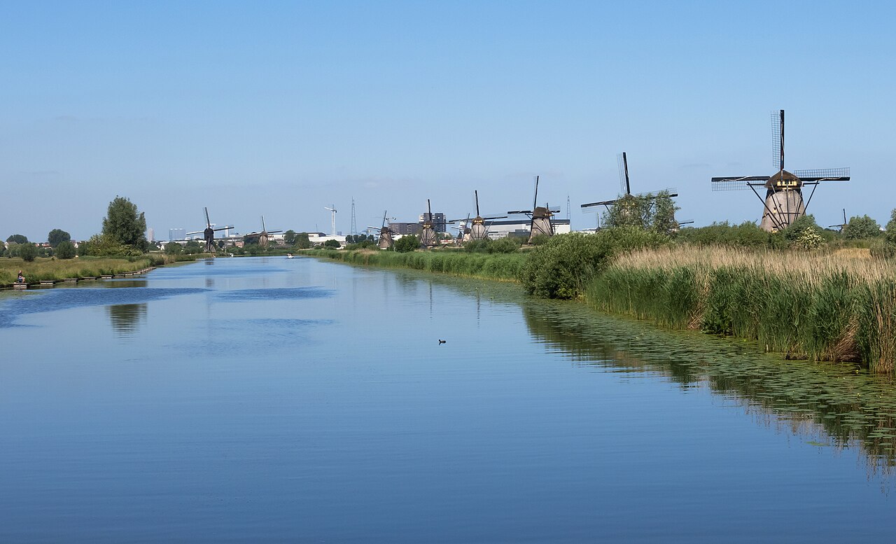 Les moulins à vent de Kinderdijk alignés le long d’un canal bordé de roseaux, sous un ciel bleu d’été, aux Pays-Bas