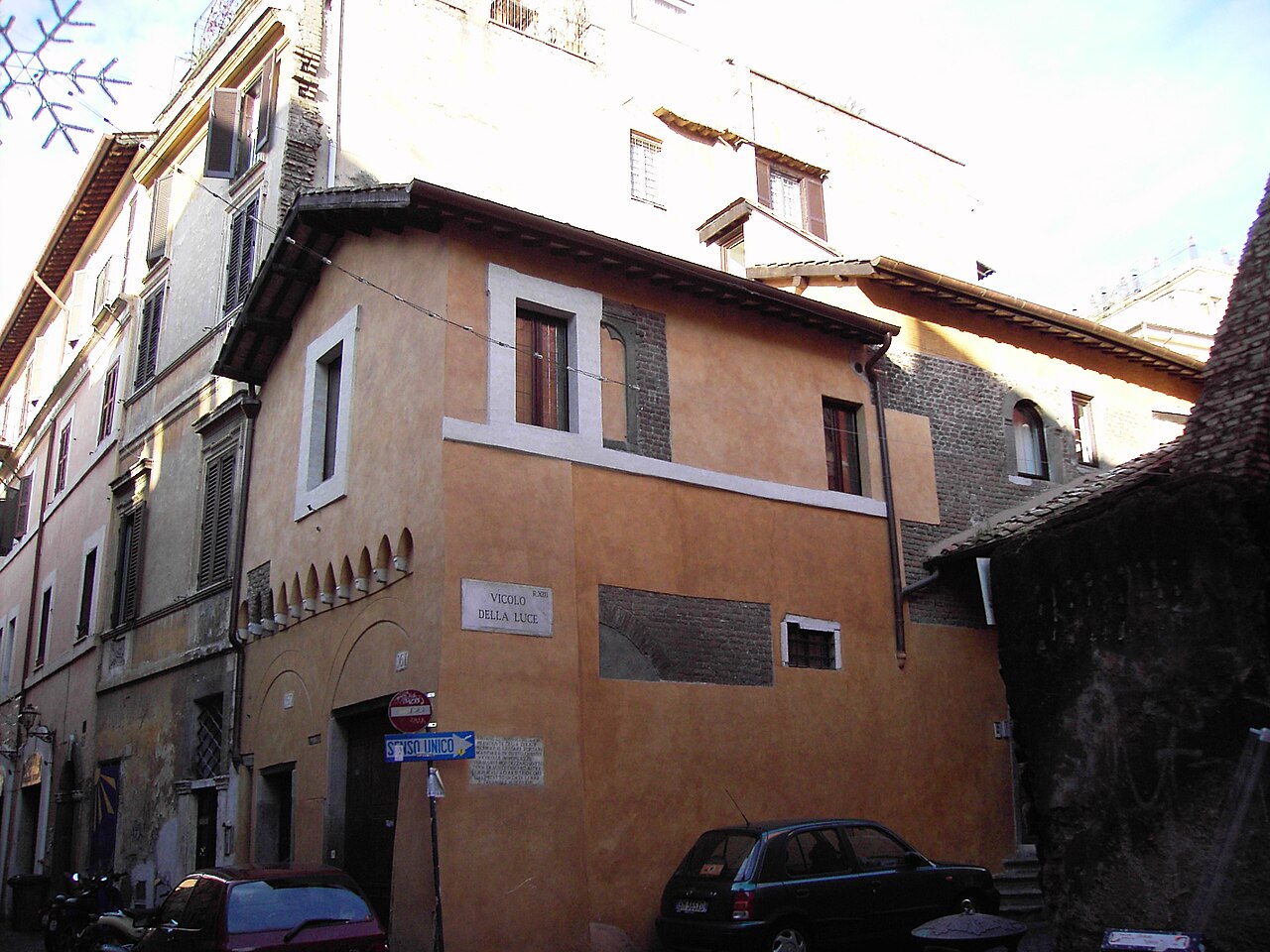 Une maison médiévale crépie d’ocre à l’angle du vicolo della Luce, dans le Trastevere, avec sa corniche de briques et ses fenêtres anciennes