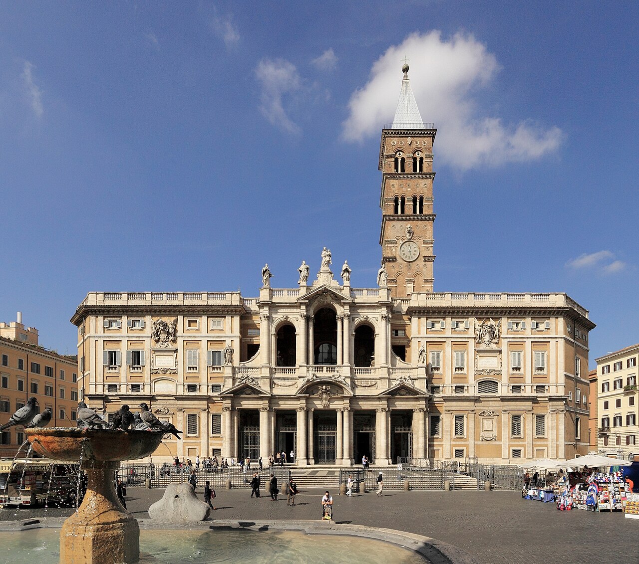 La façade de Sainte-Marie-Majeure et son haut campanile roman, vus de la place, une fontaine et des pigeons au premier plan