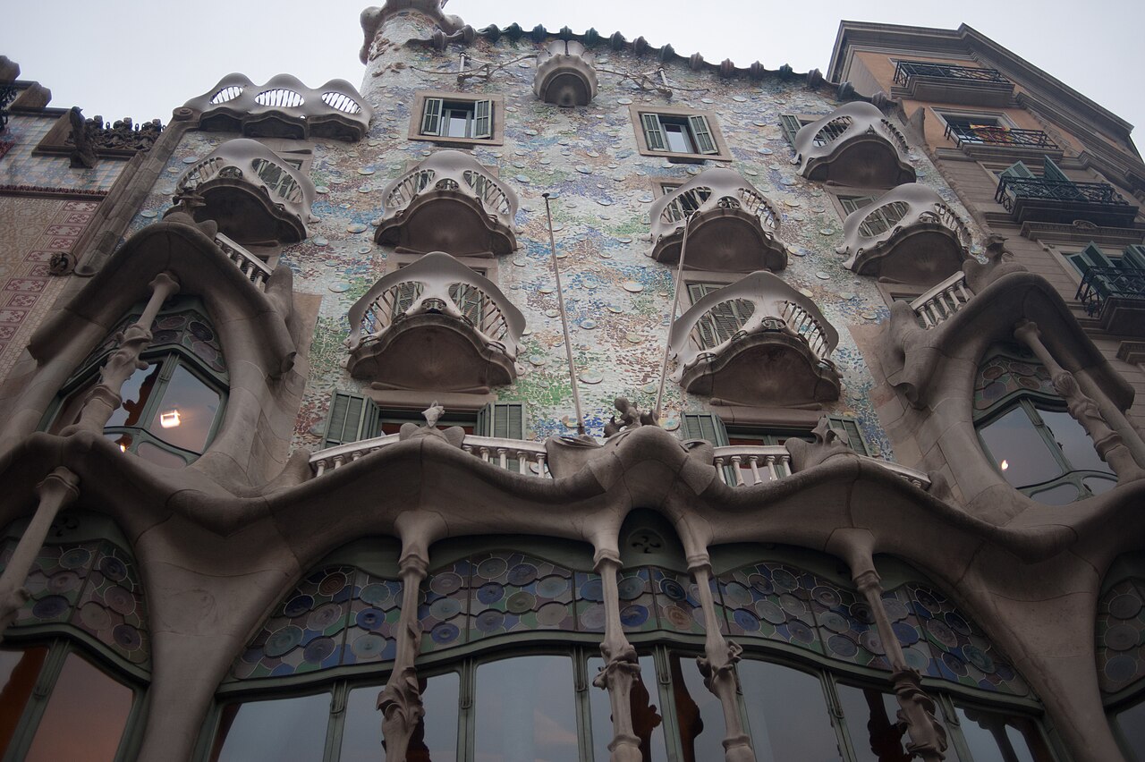 La façade de la Casa Batlló vue d’en bas : balcons en forme de masques, colonnes osseuses et mosaïque bleutée