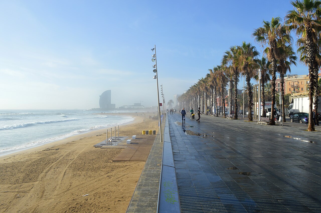 La plage de la Barceloneta hors saison et sa promenade bordée de palmiers, avec l’hôtel en forme de voile au loin