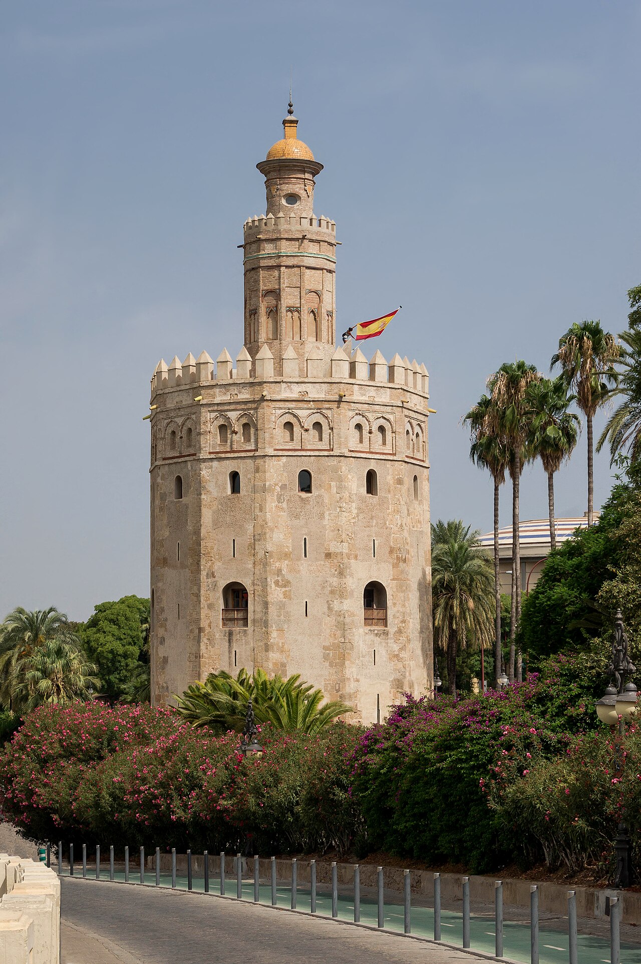 La Torre del Oro au bord du Guadalquivir, entre les palmiers et les lauriers-roses, drapeau espagnol au sommet