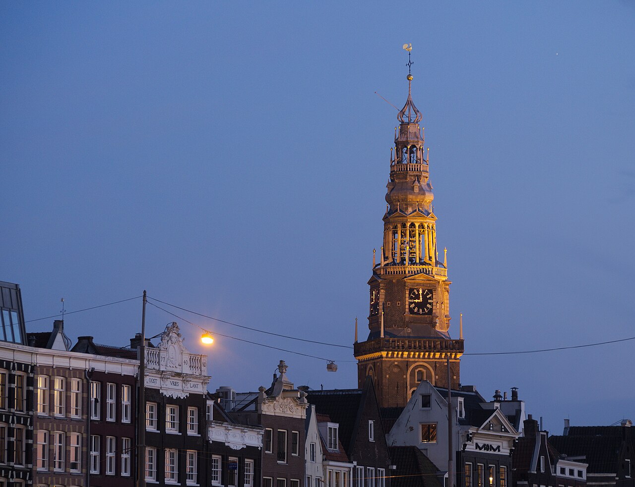 Le clocher illuminé de l’Oude Kerk au-dessus des pignons du vieil Amsterdam, au crépuscule