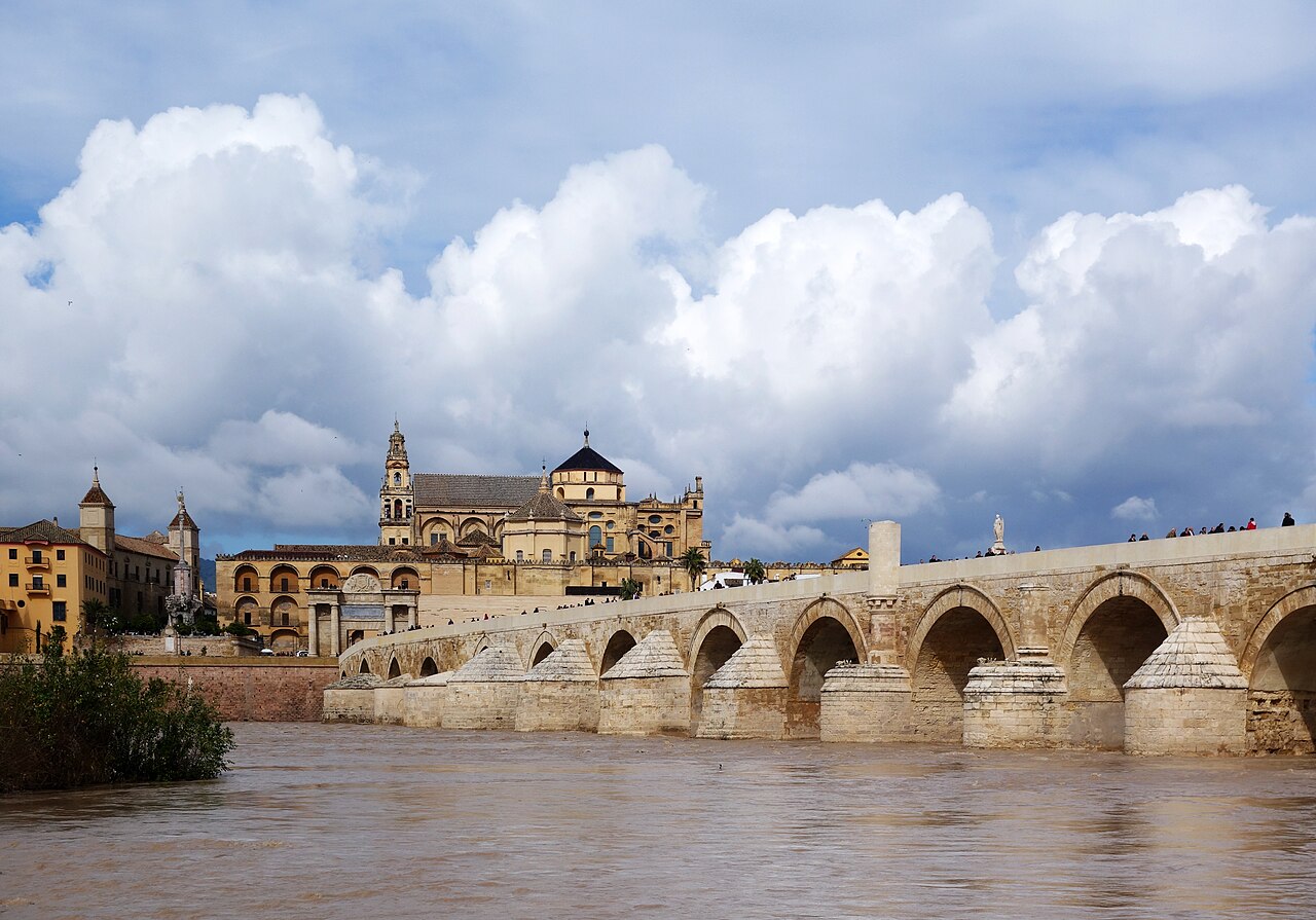 Le pont romain de Cordoue sur le Guadalquivir, avec la Mosquée-Cathédrale derrière, sous un ciel nuageux